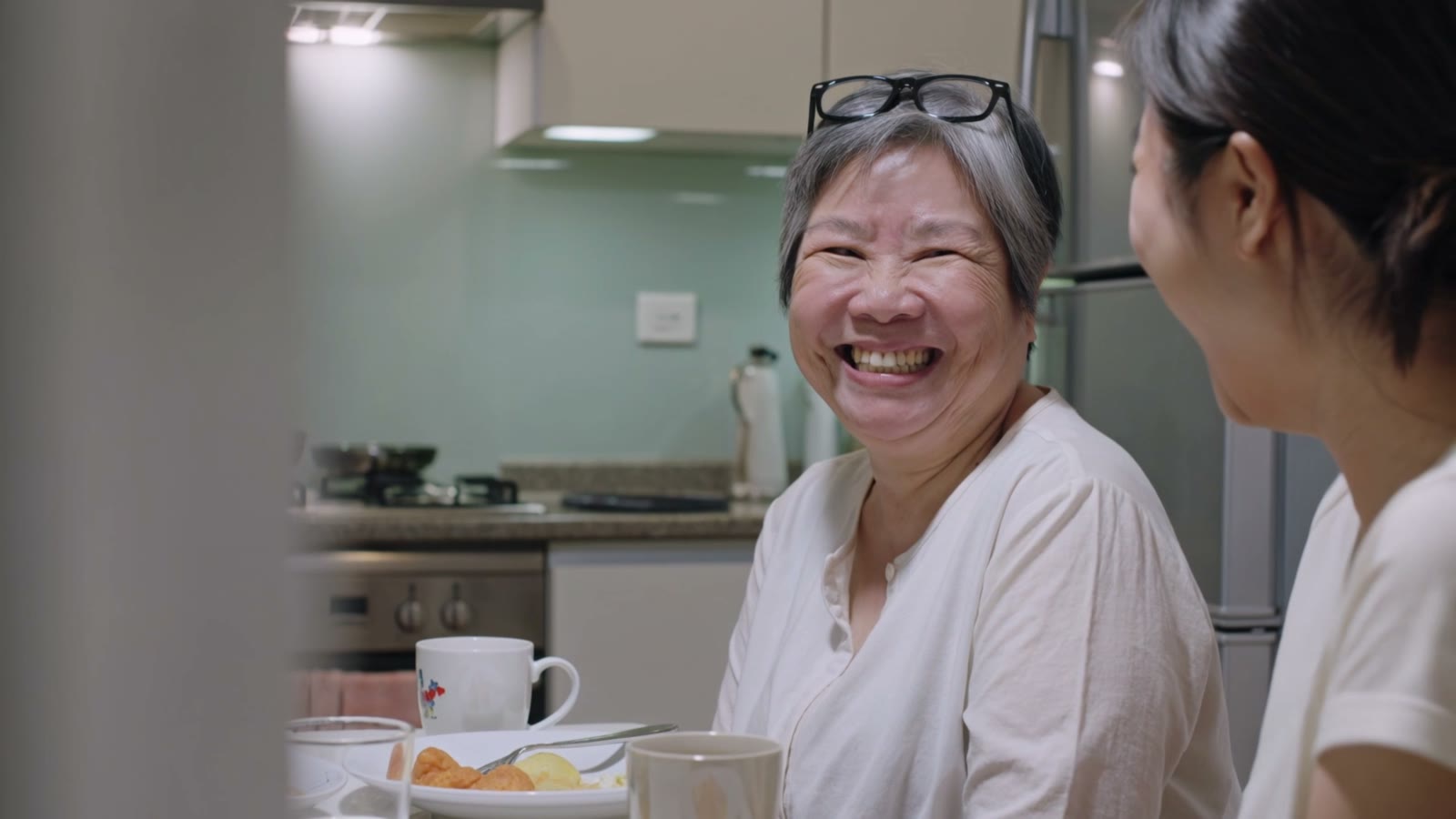 A grandmother laughing with her family at the dinner table
